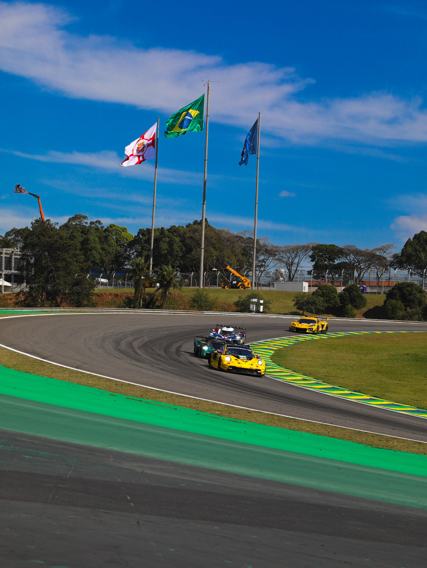 Porsche and Corvette GT cars through the corner beneath the flagpoles