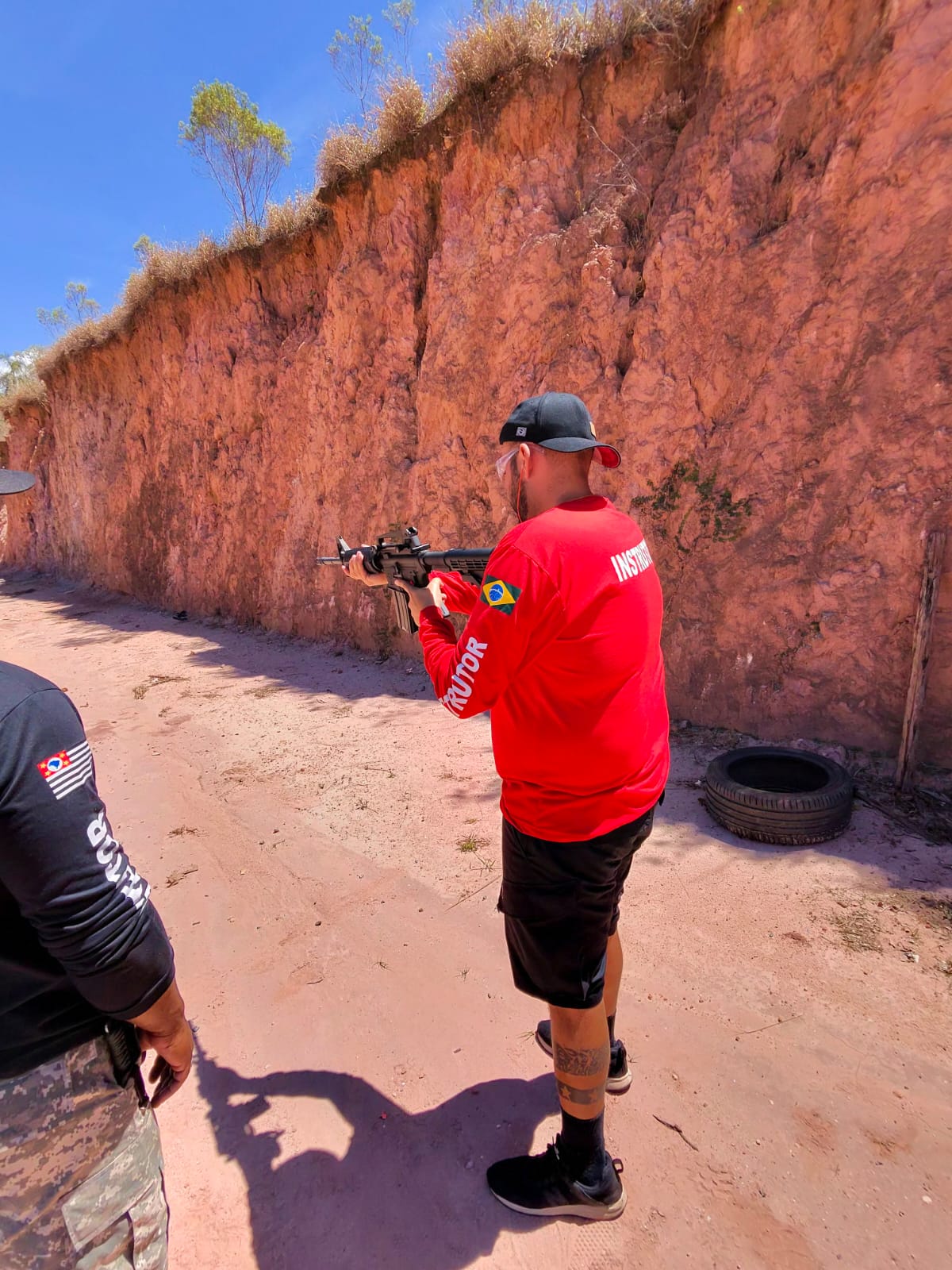 Instructor shooting along a red clay wall at the range