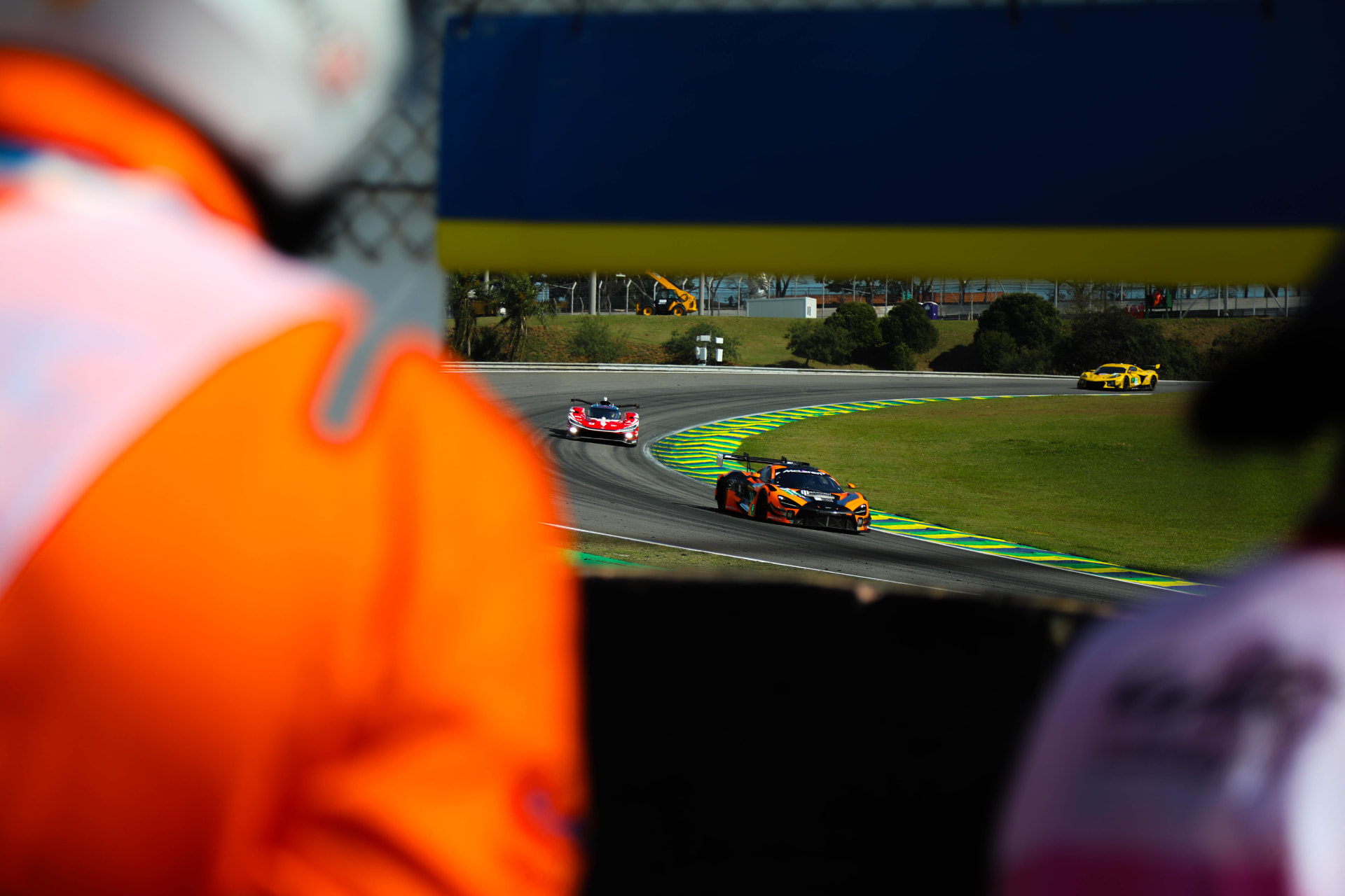 Orange McLaren GT3 framed between two trackside marshals