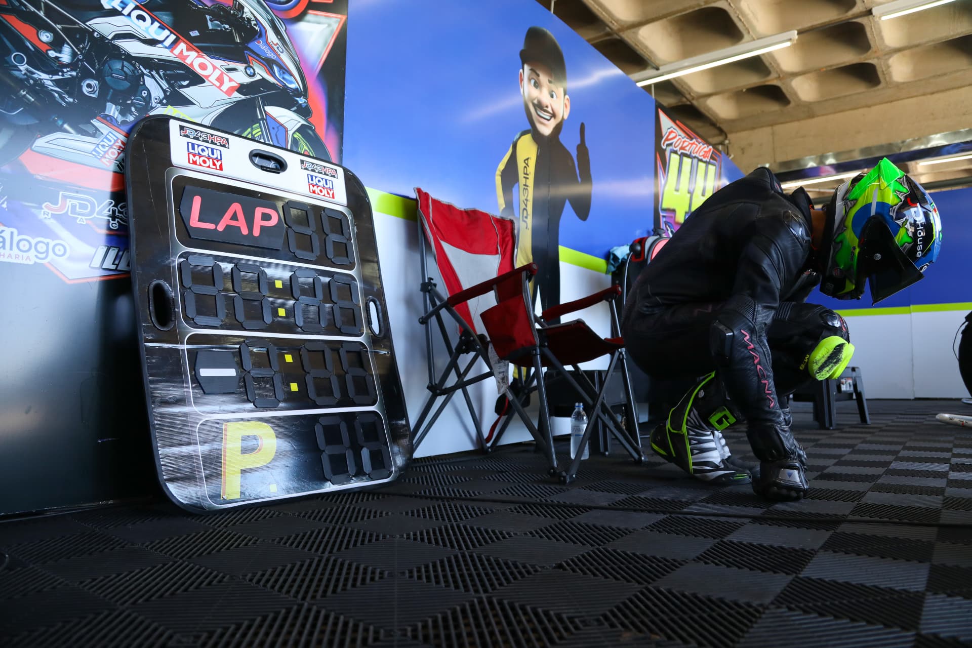 Rider putting on his boots beside the pit board in the garage