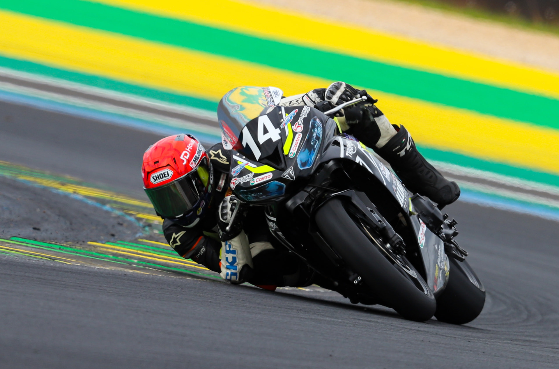 Rider number 14 cutting the green and yellow kerbs