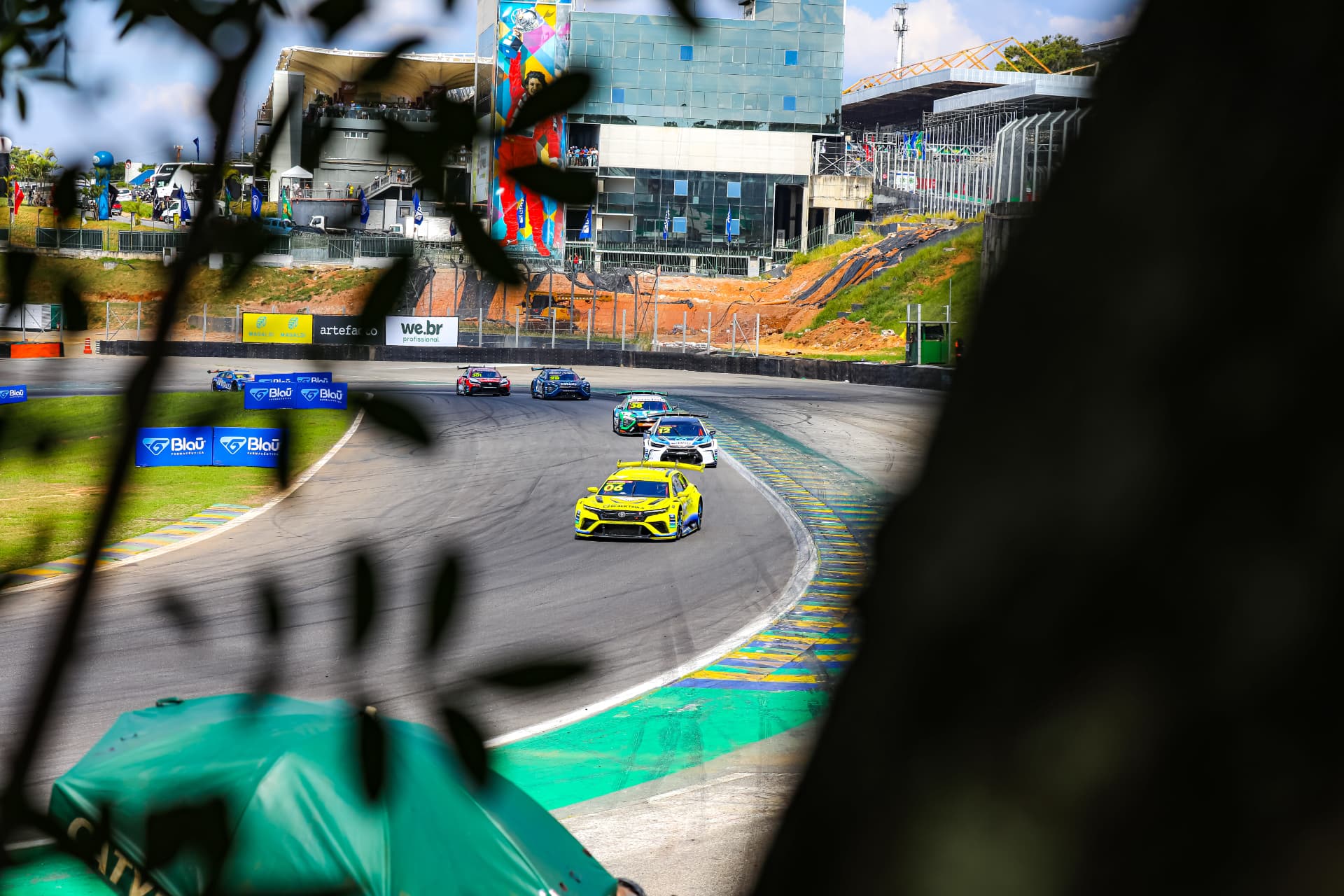 Stock cars cornering below the Senna mural at Interlagos