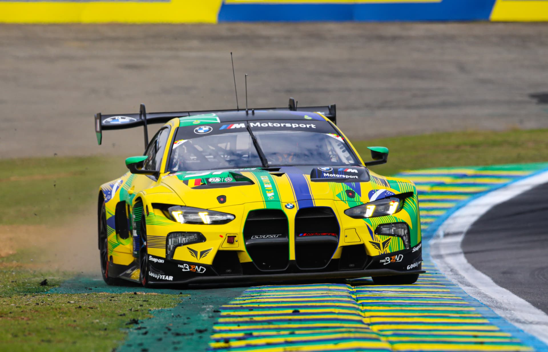 BMW M4 GT3 in Brazilian livery cresting the kerbs at Interlagos