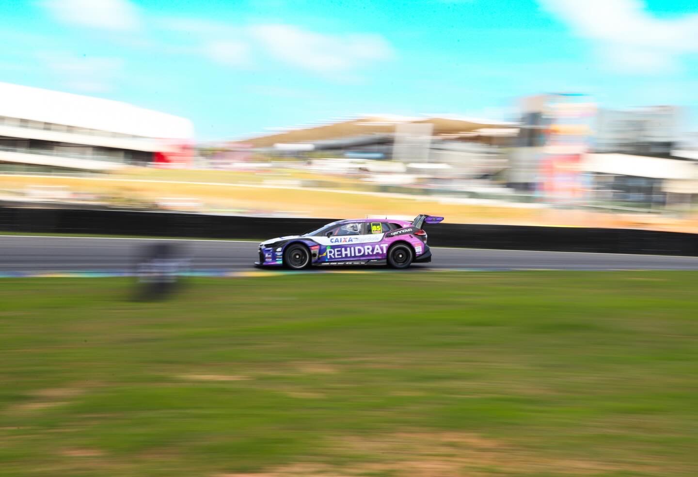 Panning shot of the Rehidrat stock car at speed past the grandstands