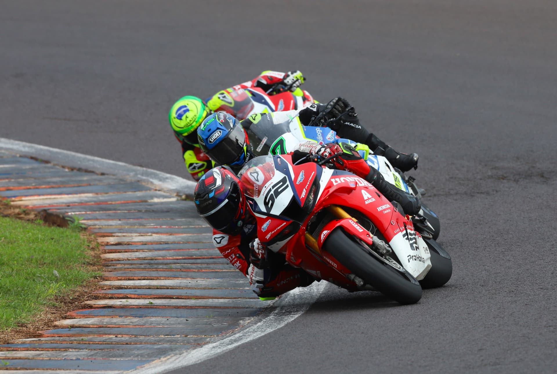 Honda superbike leading a pack of riders through a kerbed corner