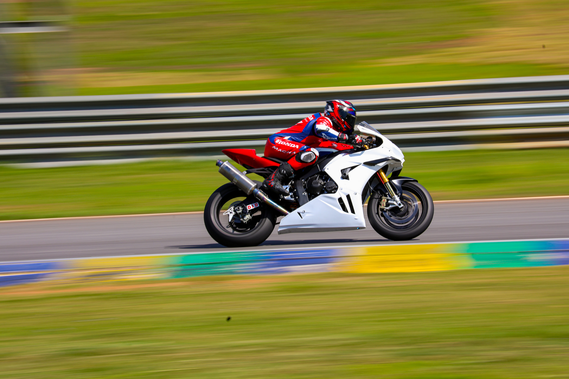Honda rider panning past the guardrail on the back straight