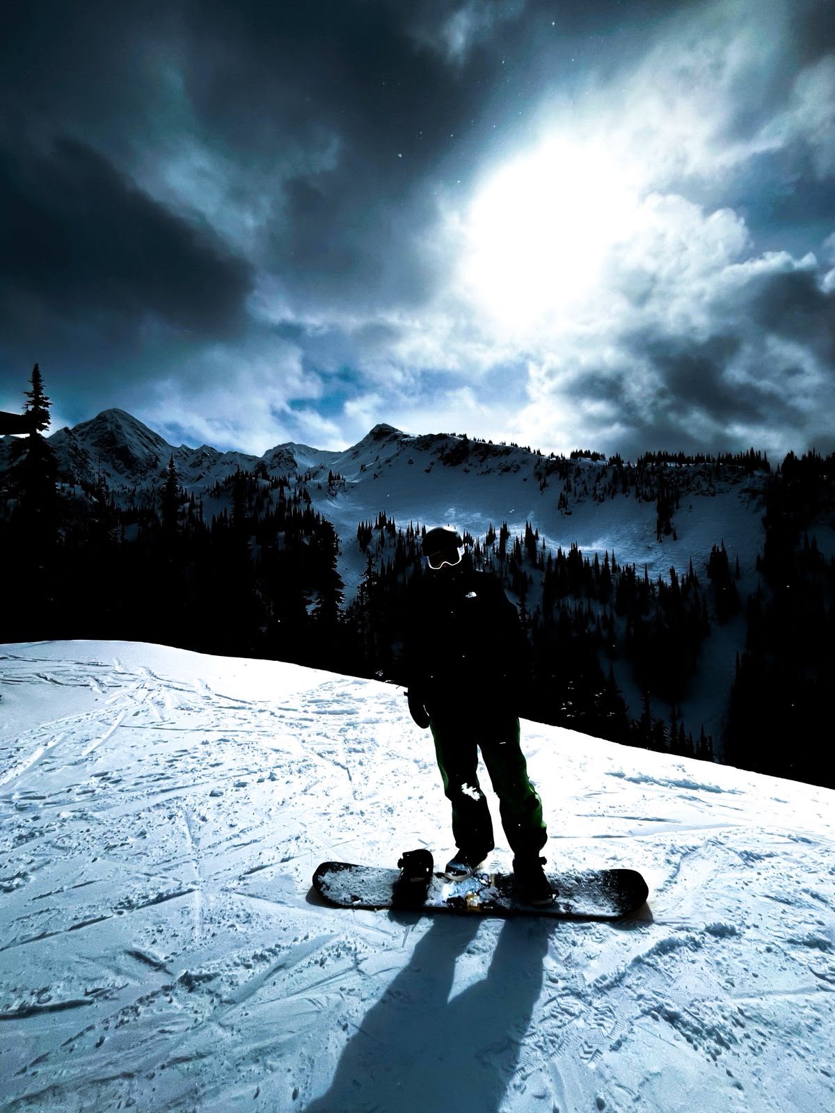 Snowboarder silhouetted against dramatic mountain clouds