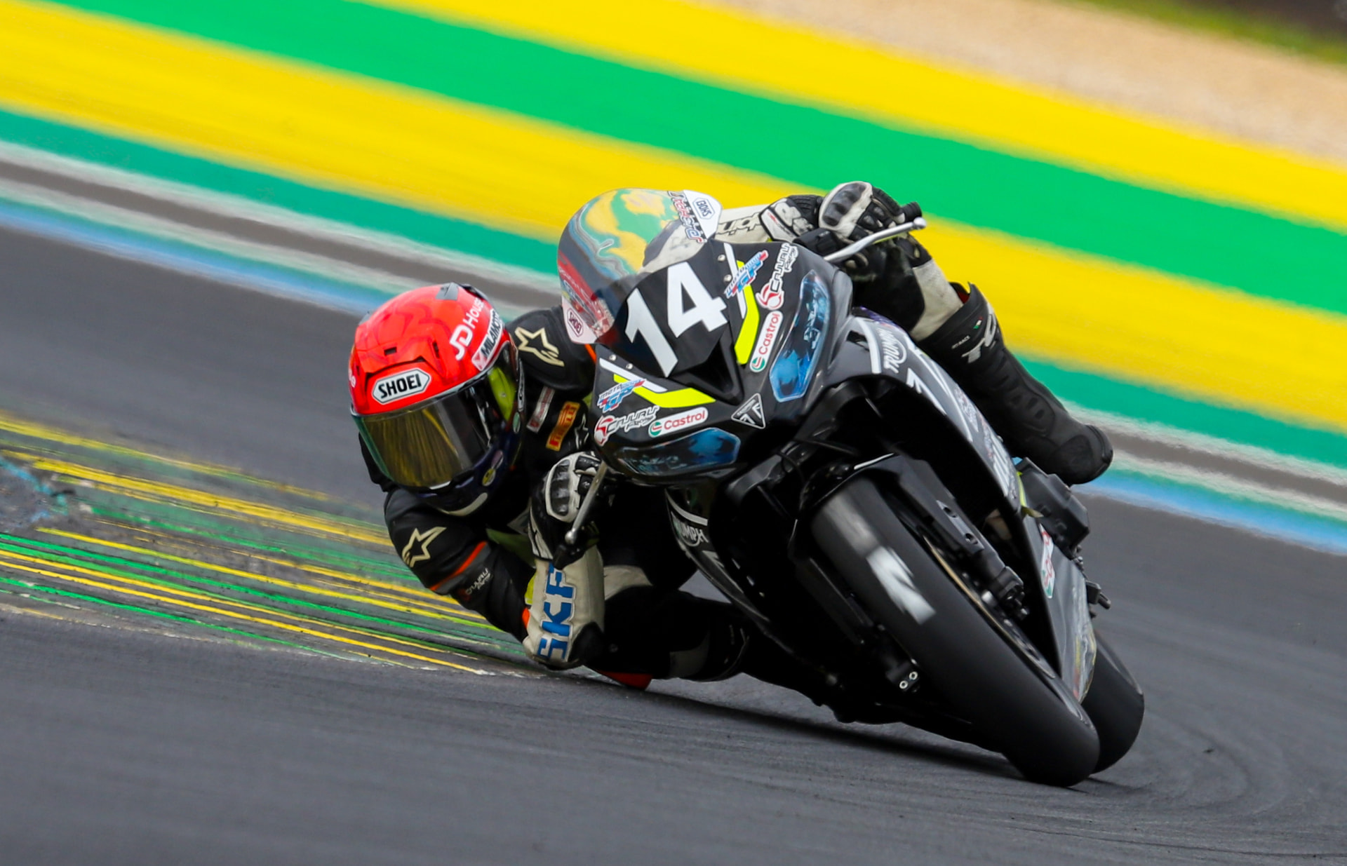 Triumph rider number 14 leaning into the corner at speed